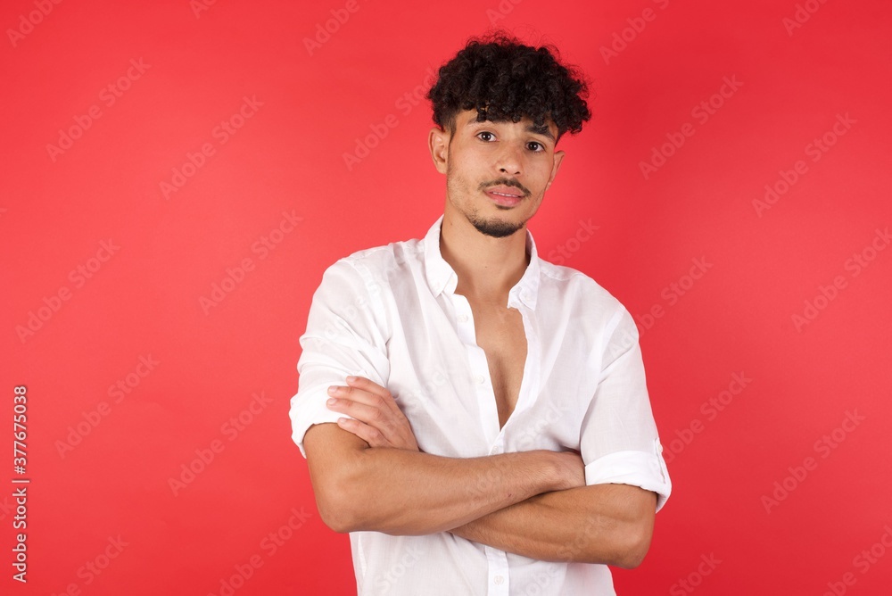Young arab man with afro hair wearing shirt standing over isolated red background happy face smiling with crossed arms looking at the camera. Positive person. Young arab man with afro hair wearing shirt standing over isolated red background happy face smiling with crossed arms looking at the camera. Positive person.