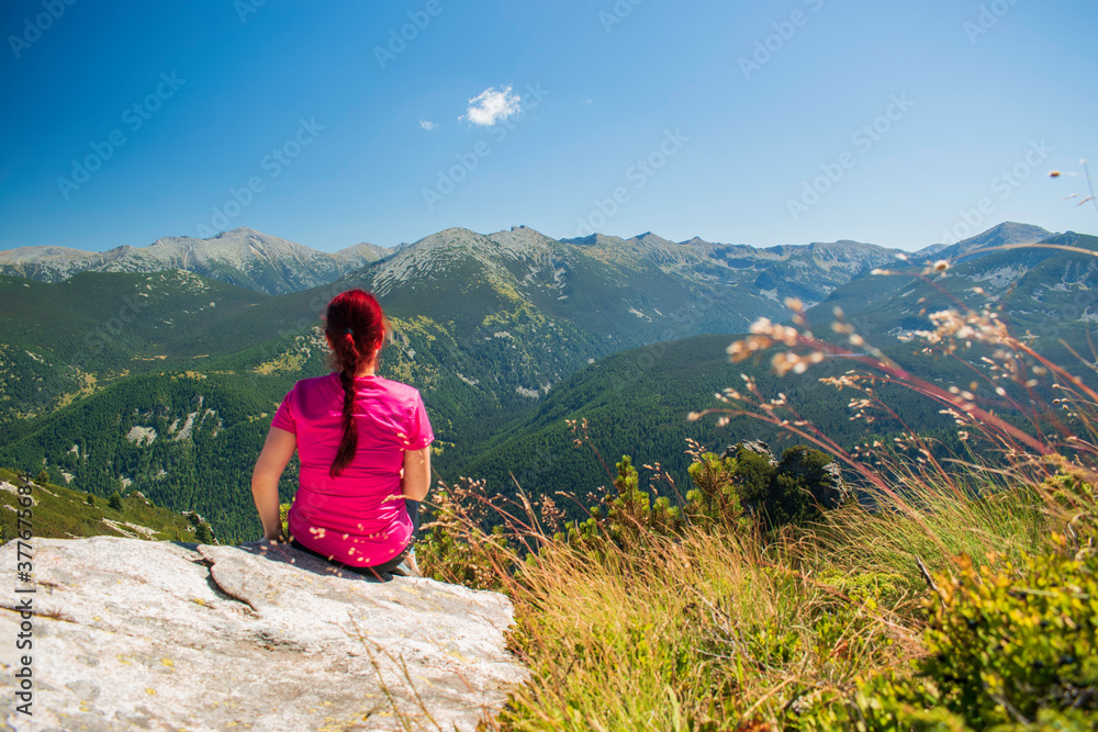 Young lady enjoying the scenery on the top of a mountain peak.