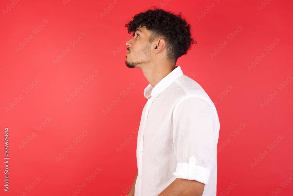 Close up side profile photo Young arab man with afro hair wearing shirt standing over isolated red background ready to have a walk. Close up side profile photo Young arab man with afro hair wearing shirt standing over isolated red background ready to have a walk.