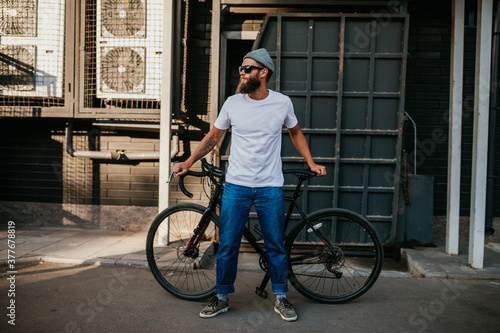 Young bearded hipster guy wearing white blank t-shirt with bicycle . Mock-up for print. T-shirt template. photo