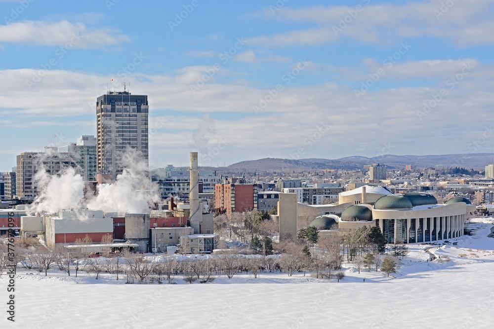 Highrise office towers, industrial buildings and national history museumin Hull district in winter, along frozen Ottawa river.