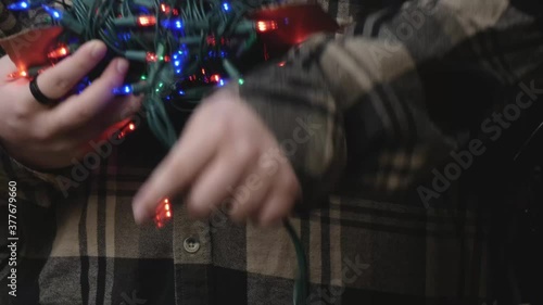 man using a ladder to set up christmas lights