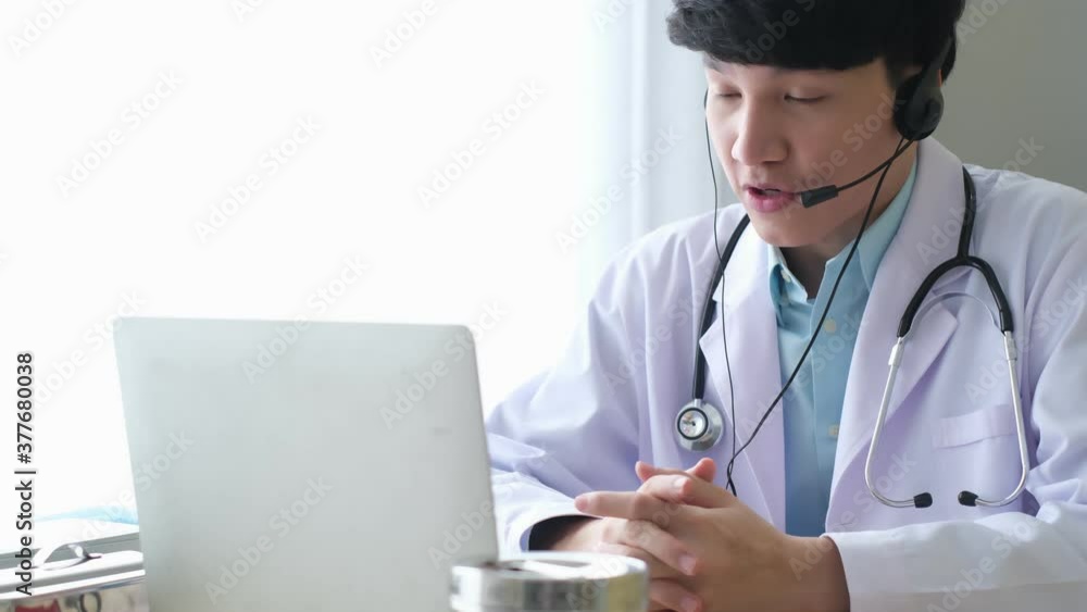 Professional male doctor imedical assistant wears white coat, headset video calling distant patient on laptop. Doctor talking to client using virtual chat computer app. Telemedicine. Professional male doctor imedical assistant wears white coat, headset video calling distant patient on laptop. Doctor talking to client using virtual chat computer app. Telemedicine.