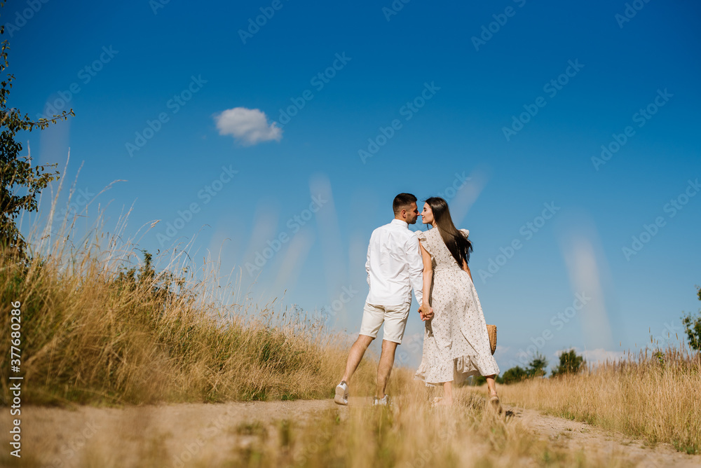 Young couple in the wheat field on sunny summer day. Couple in love have fun in golden field. Romantic couple in casual clothe outdoodrs on boundless field Young couple in the wheat field on sunny summer day. Couple in love have fun in golden field. Romantic couple in casual clothe outdoodrs on boundless field