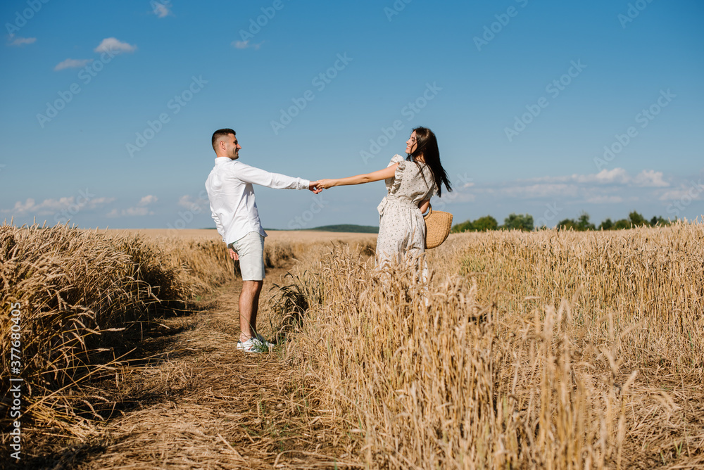 Young couple in the wheat field on sunny summer day. Couple in love have fun in golden field. Romantic couple in casual clothe outdoodrs on boundless field Young couple in the wheat field on sunny summer day. Couple in love have fun in golden field. Romantic couple in casual clothe outdoodrs on boundless field