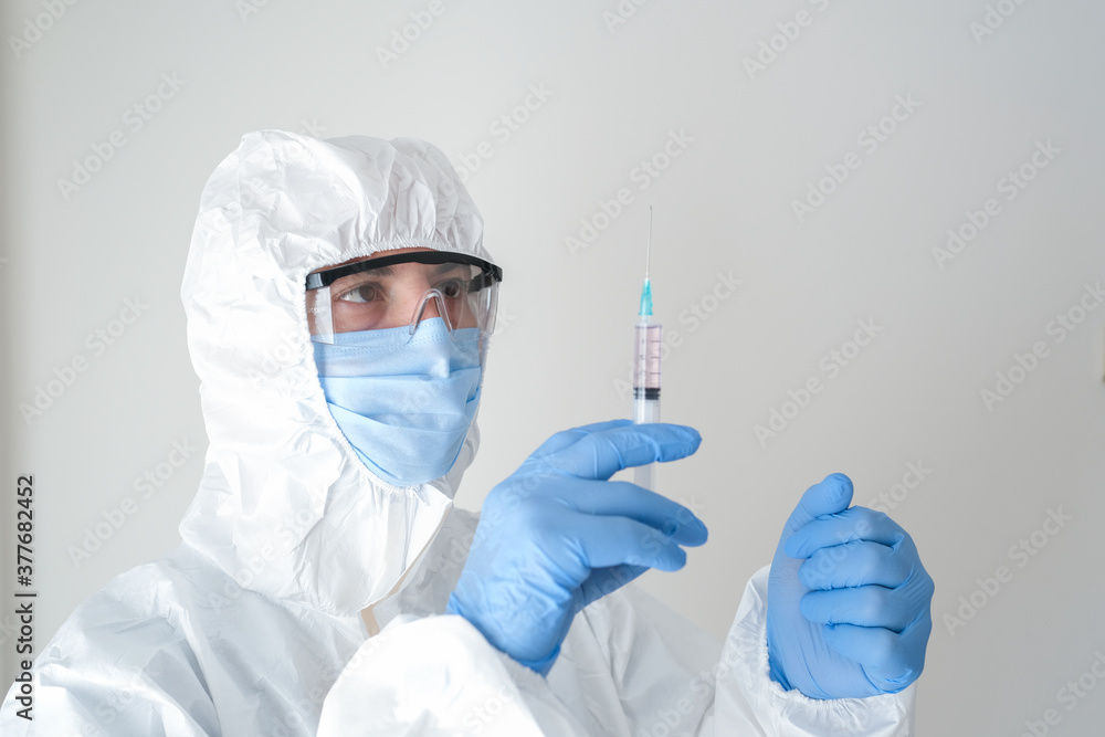 fully sheltered doctor holding syringe in hand. Young doctor preparing for vaccination. fully sheltered doctor holding syringe in hand. Young doctor preparing for vaccination.