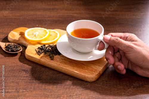 Cup of freshly tea with yellow lemon on black