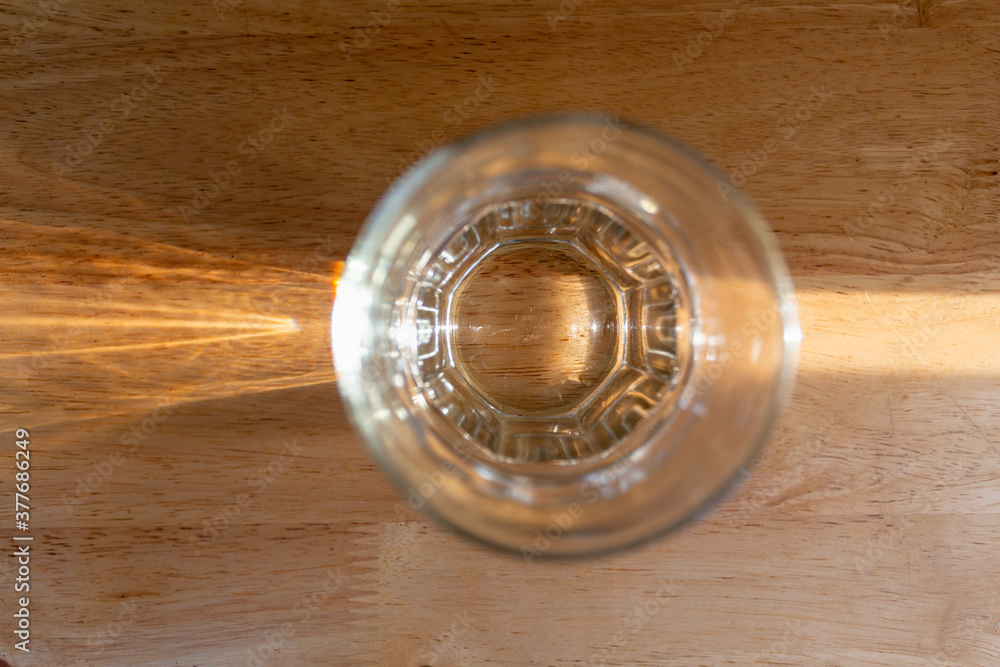 Glass of water on wood table with light ray, top view Glass of water on wood table with light ray, top view