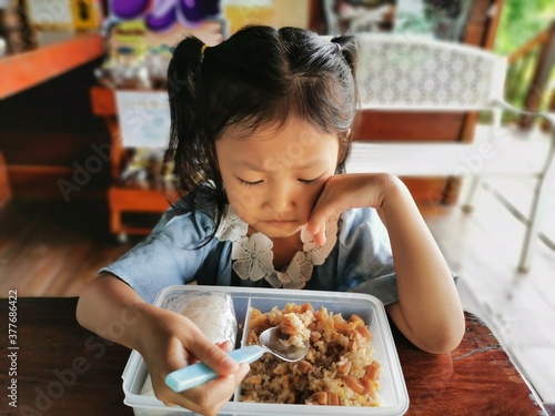 A little girl eating with a spoon.
