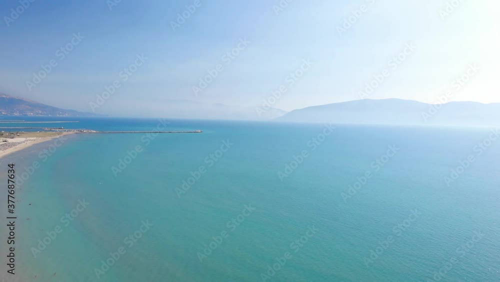 Beach umbrellas on sand washed by calm clear water of turquoise sea in Mediterranean.