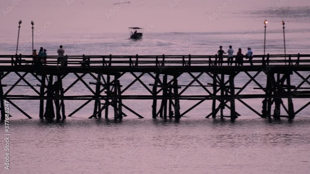 The Mon Bridge is an old wooden bridge located in Sangkla, Thailand. Monks and people cross before sunrise to earn merits and take blessings; in the afternoon, a leisure place to meet friends. The Mon Bridge is an old wooden bridge located in Sangkla, Thailand. Monks and people cross before sunrise to earn merits and take blessings; in the afternoon, a leisure place to meet friends.