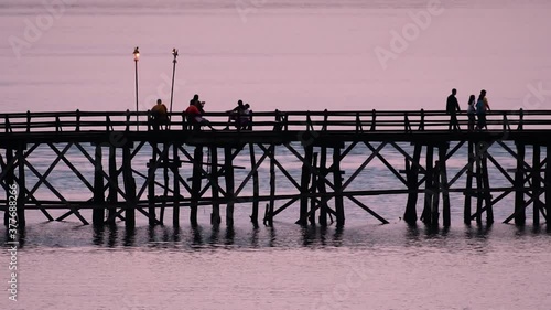 The Mon Bridge is an old wooden bridge located in Sangkla, Thailand. Monks and people cross before sunrise to earn merits and take blessings; in the afternoon, a leisure place to meet friends. photo