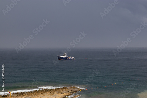 Sliema coastline with beach stone, Malta. sea view with boat. bad weather at sea