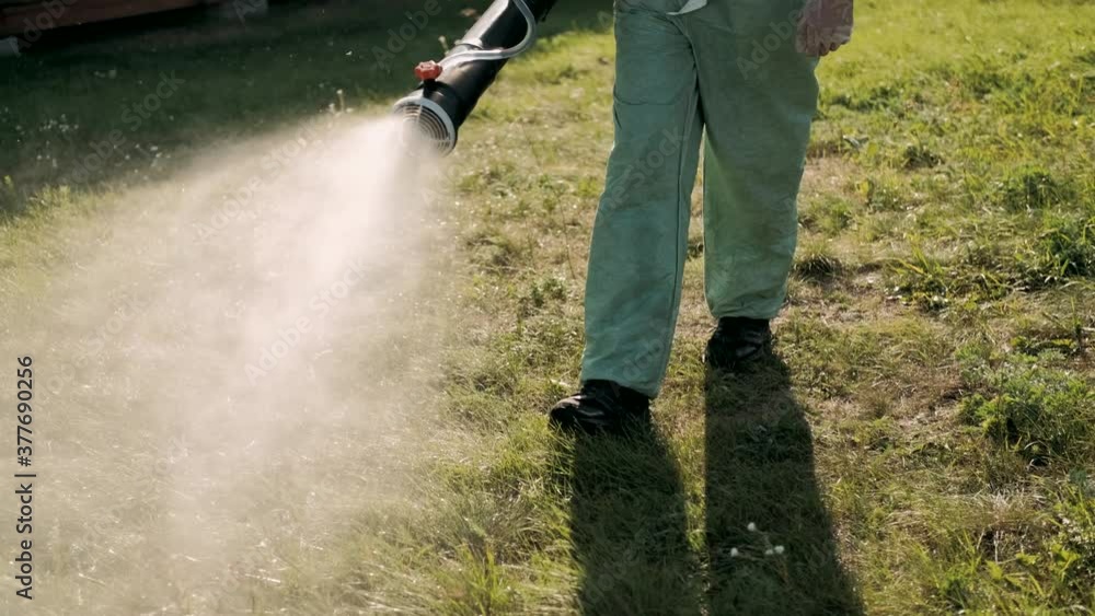 Farmer in protective clothes spray pesticides. Farm worker spray