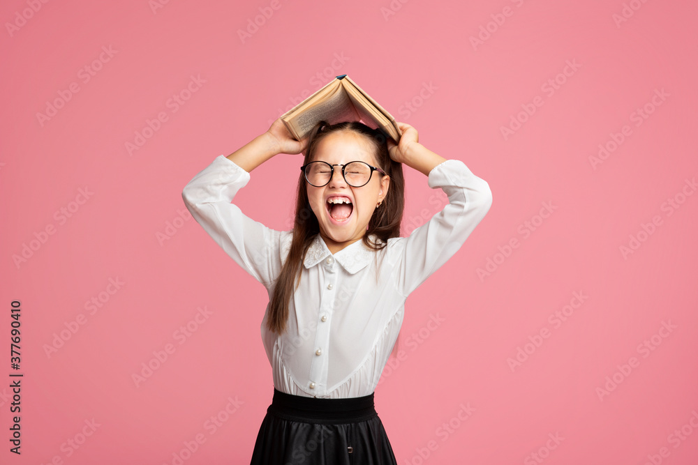 Oh no, i hate to study. Schoolgirl in uniform and glasses screams and holds book on her head