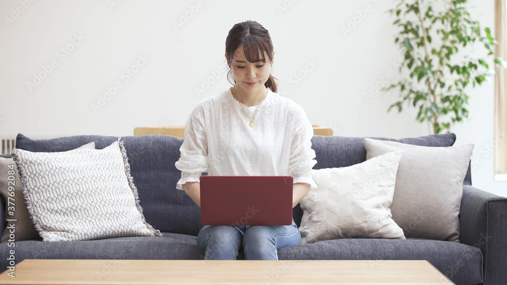 ソファーでラップトップをタイピングする若い女性 ソファーでラップトップをタイピングする若い女性