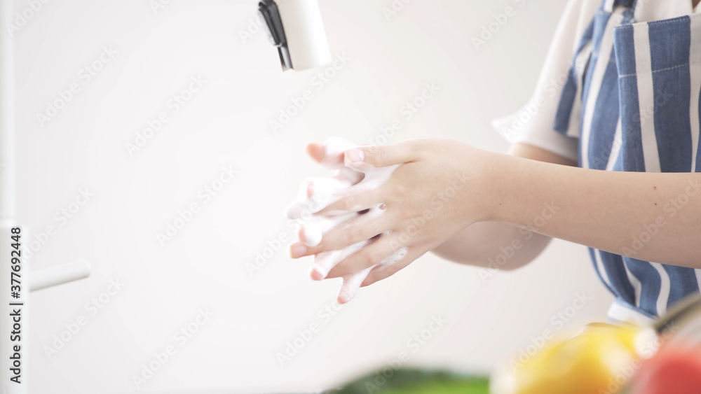 キッチンで手を洗う若い女性	