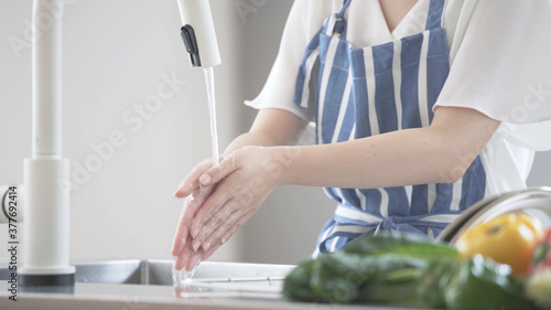 キッチンで手を洗う若い女性 