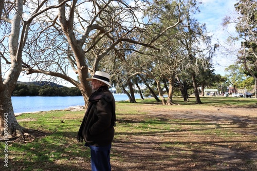 Male senior white hat beach lake trees green environment. Peninsula in The Central Coast of Australia.