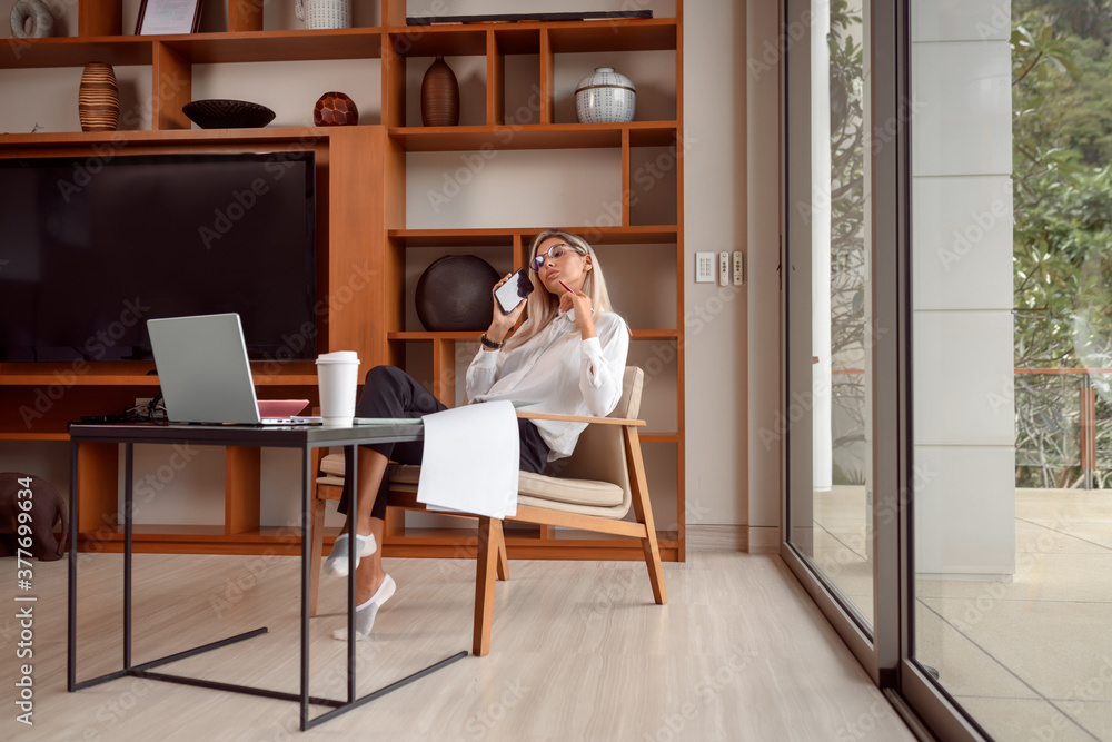 Serious businesswoman decides issues, talking on the phone, woman sits at a work table Serious businesswoman decides issues, talking on the phone, woman sits at a work table