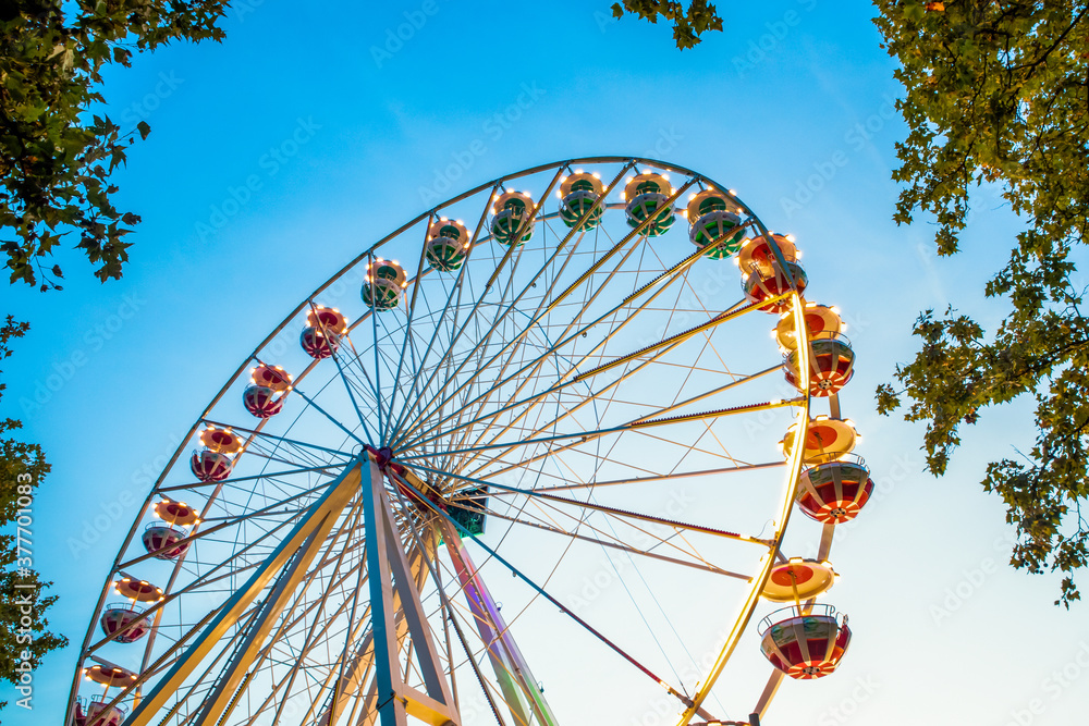 Ferries wheel at amusement park against blue sky.