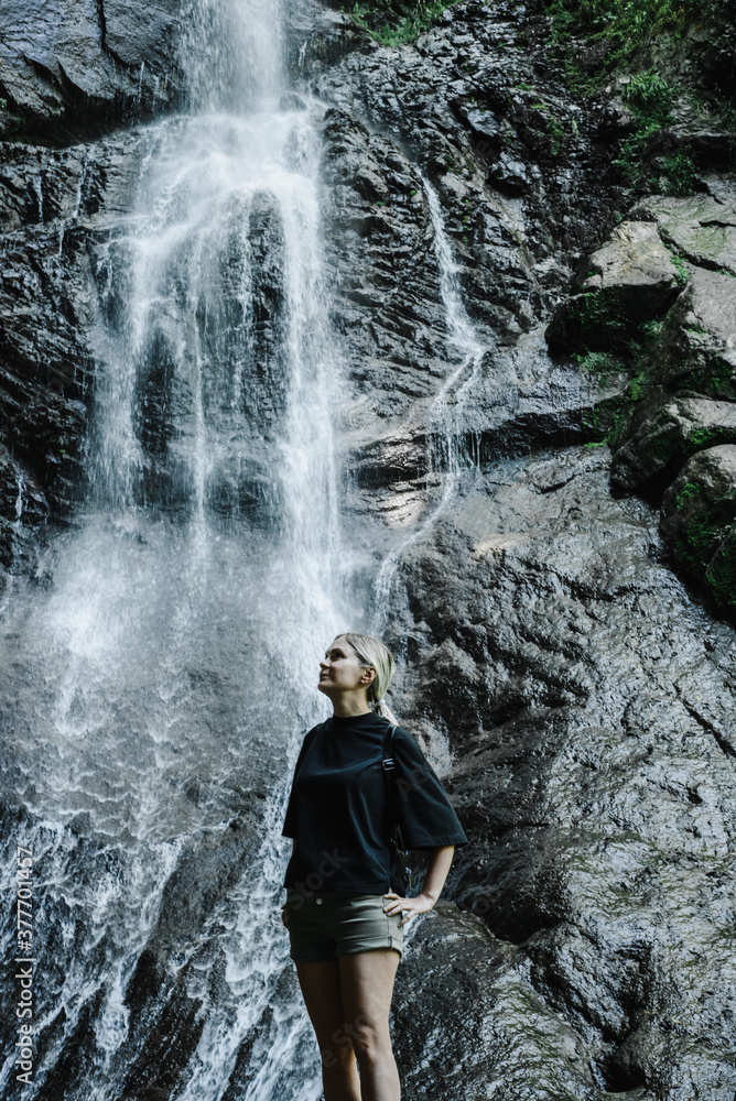 young woman on the background of a mountain waterfall with a ponytail young woman on the background of a mountain waterfall with a ponytail