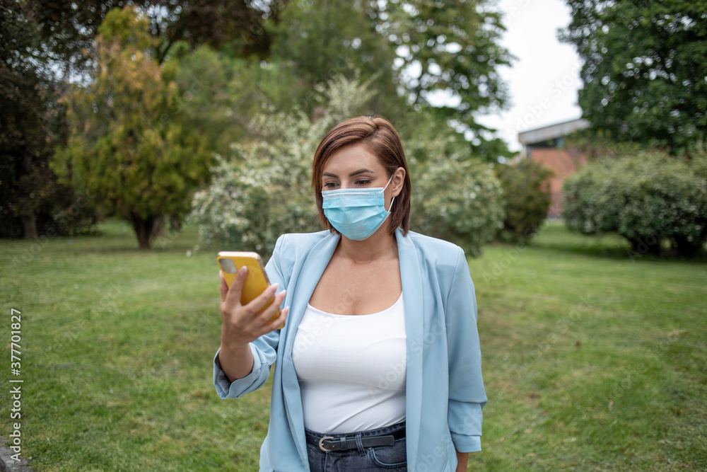 Woman with face mask using phone outdoor stock photo Woman with face mask using phone outdoor stock photo