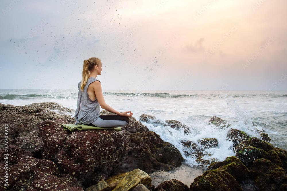 Young woman on the beach practices yoga at seashore Young woman on the beach practices yoga at seashore