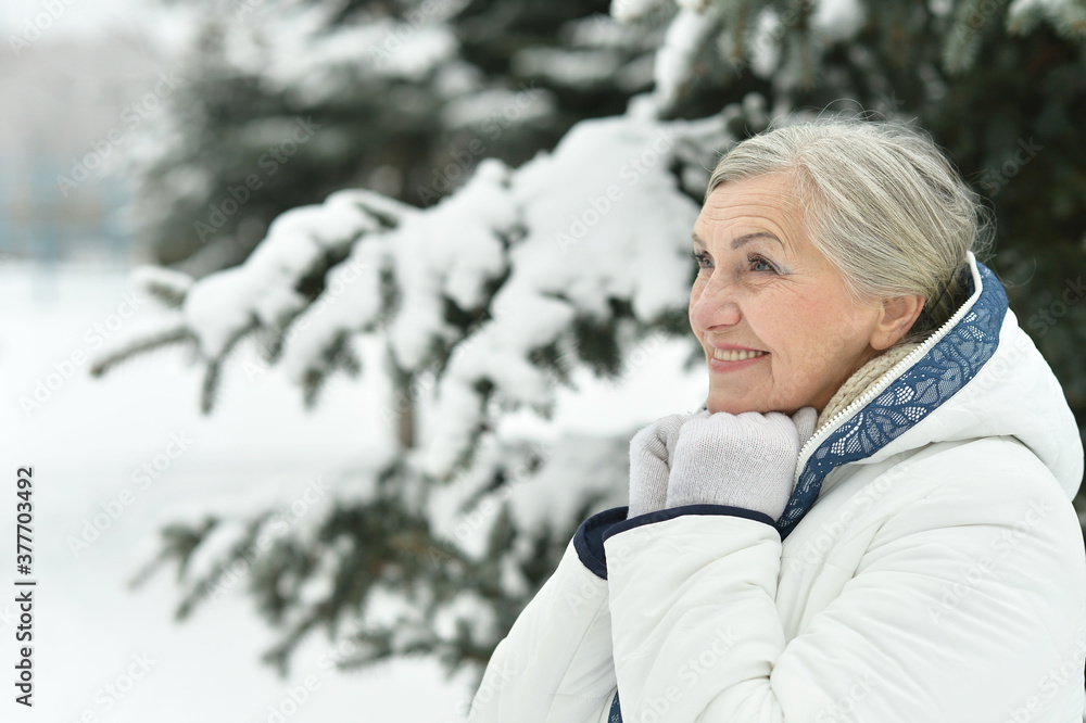 Happy beautiful senior woman posing in snowy winter park Happy beautiful senior woman posing in snowy winter park