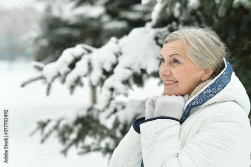 Happy beautiful senior woman posing in snowy winter park