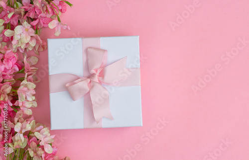 Pink flowers and a gift box on pink background. Space for text © Ken