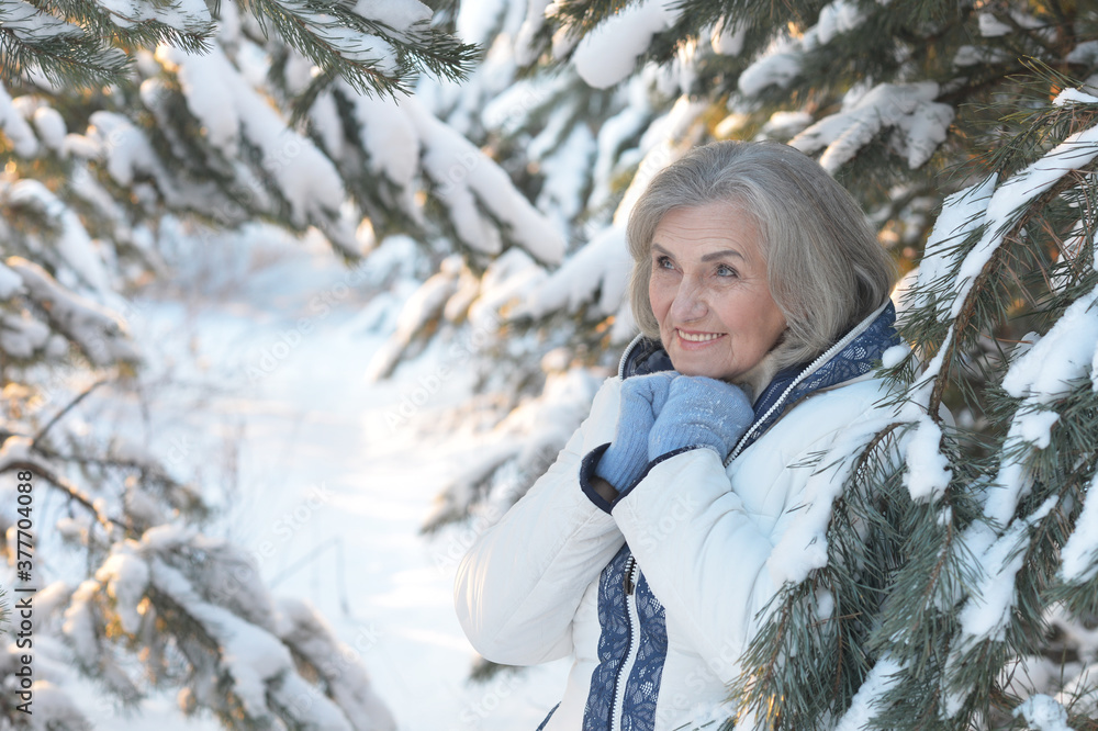 Happy beautiful senior woman posing in snowy winter park Happy beautiful senior woman posing in snowy winter park