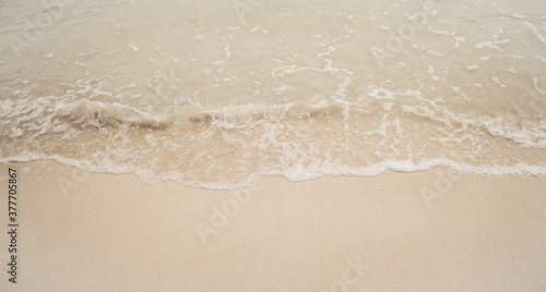 Ocean wave on sandy beach background