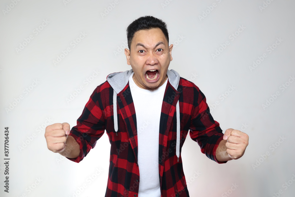 Young Asian man shouting loud because of anger. Concept of rage aggression mad frustration Young Asian man shouting loud because of anger. Concept of rage aggression mad frustration
