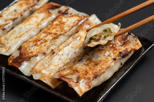 Material of traditional chinese fried dumplings(also called gyoza,pot sticker) on black background with chopsticks.