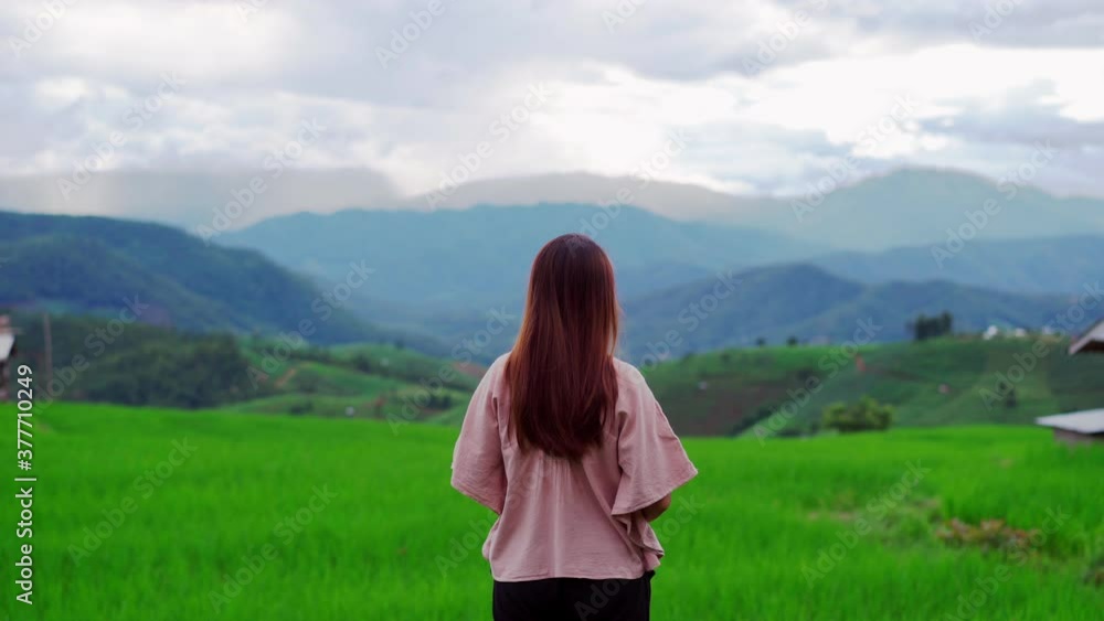 Young woman traveler on vacation enjoying and looking at beautiful green rice terraces field in Pa Pong Pieng, Chiangmai Thailand. Young woman traveler on vacation enjoying and looking at beautiful green rice terraces field in Pa Pong Pieng, Chiangmai Thailand.