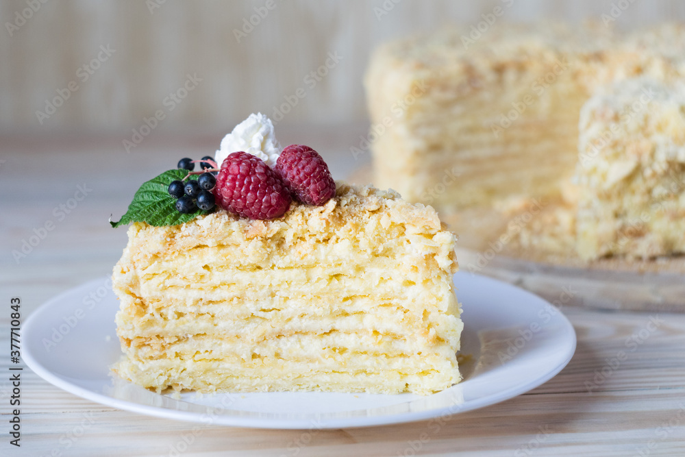 Piece of napoleon cake. Creamy vanilla slice dessert on plate. Delicious pastry served with raspberry. Layered baked pie on white plate. Selective focus Piece of napoleon cake. Creamy vanilla slice dessert on plate. Delicious pastry served with raspberry. Layered baked pie on white plate. Selective focus