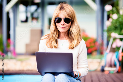 Attractive woman using her notebook while sitting in the garden at home