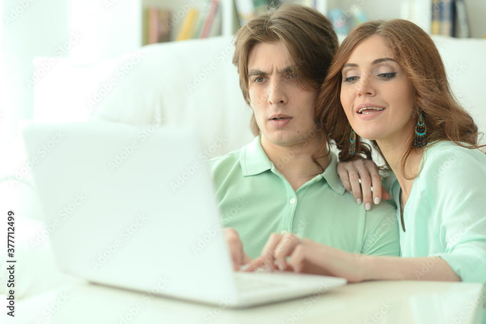 Young couple hugging and looking at laptop at home Young couple hugging and looking at laptop at home