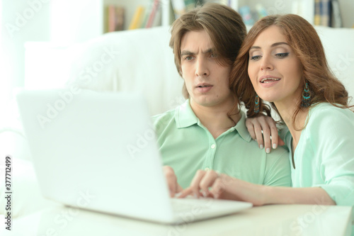 Young couple hugging and looking at laptop at home © aletia2011