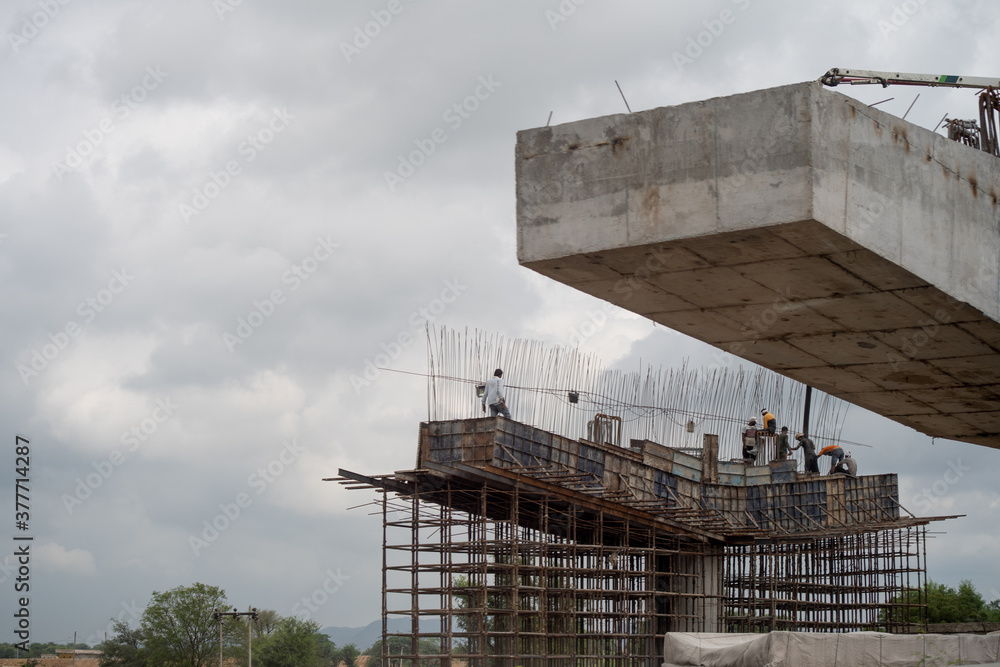 Labor and workers standing on a support for a bridge under construction ...