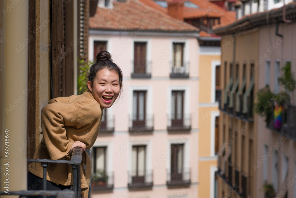 young happy and beautiful Asian Korean woman in hair bun enjoying city view from hotel room balcony in Spain during holidays trip in Europe smiling cheerful in urban background young happy and beautiful Asian Korean woman in hair bun enjoying city view from hotel room balcony in Spain during holidays trip in Europe smiling cheerful in urban background