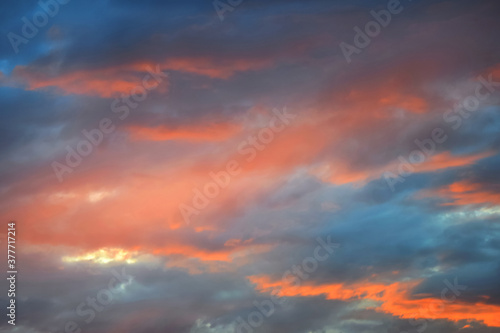 Colorful fiery sunset, dramatic sky in orange and blue colors. Natural background. Rays of light shining through dark clouds. © Marina_Nov