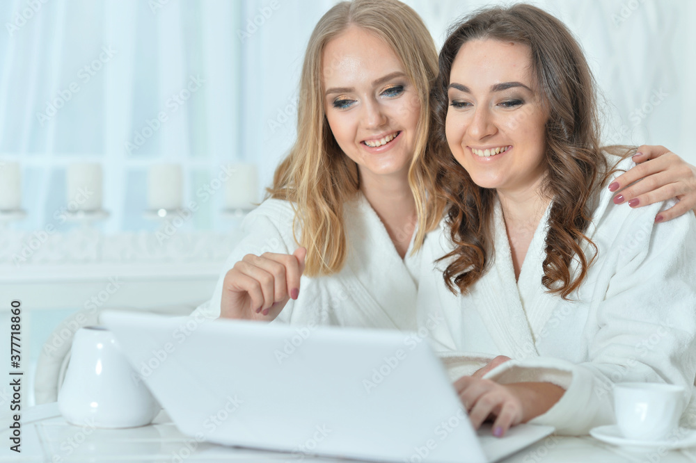 Portrait of young women in bathrobes with laptop Portrait of young women in bathrobes with laptop