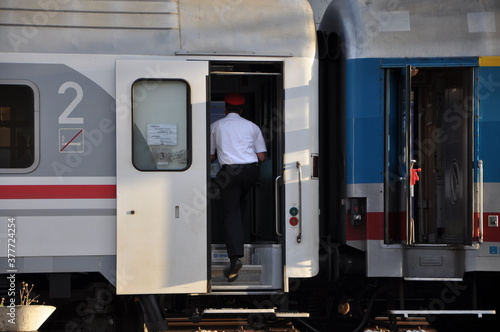 The conductor enters the passenger train in the city on central station.