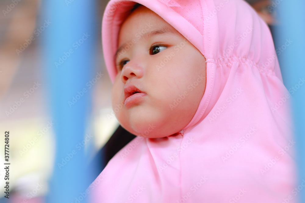 portrait of a baby girl Muslim big eyes wearing a pink hijab, red cheeks close up view portrait of a baby girl Muslim big eyes wearing a pink hijab, red cheeks close up view