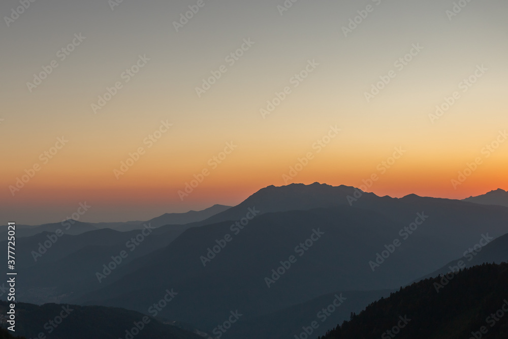 A scenic sunset in the mountains with sunlight, beautiful light. Evening summer landscape in a valley with horizon, sky, grass, flowers. Picture background nature panorama