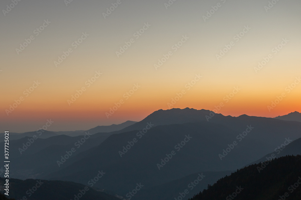 A scenic sunset in the mountains with sunlight, beautiful light. Evening summer landscape in a valley with horizon, sky, grass, flowers. Picture background nature panorama A scenic sunset in the mountains with sunlight, beautiful light. Evening summer landscape in a valley with horizon, sky, grass, flowers. Picture background nature panorama