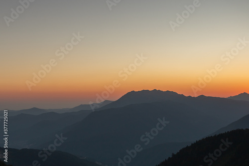 A scenic sunset in the mountains with sunlight, beautiful light. Evening summer landscape in a valley with horizon, sky, grass, flowers. Picture background nature panorama