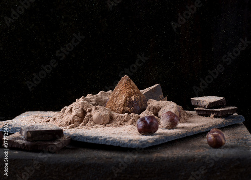 Chocolate truffle sprinkled with cacao and golden powder against the black background